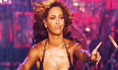 A Woman In A Very Revealing Top Is Dancing On A Stage And Pointing At The Camera . GIF