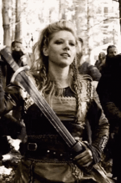 A Woman In A Viking Costume Is Holding A Sword In A Black And White Photo . GIF