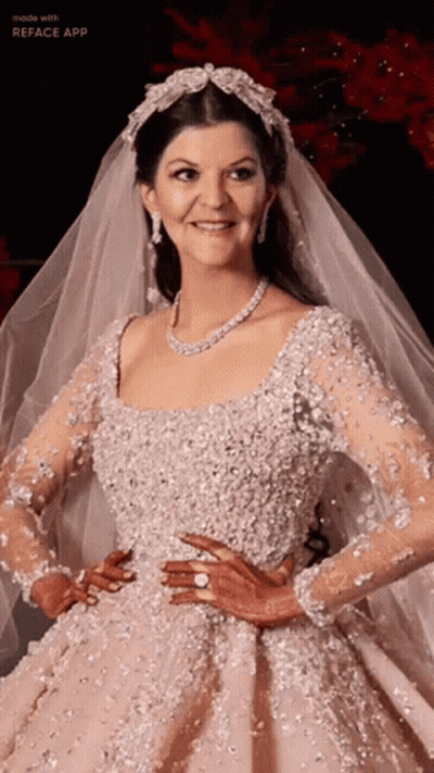 A Woman In A Wedding Dress And Veil Is Smiling GIF