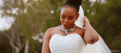 A Woman In A Wedding Dress And Veil Is Standing In Front Of A Forest . GIF