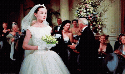 A Woman In A Wedding Dress Holds A Bouquet Of Flowers GIF