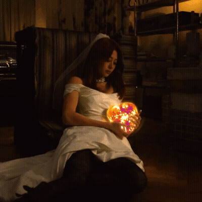 A Woman In A Wedding Dress Holds A Glowing Heart GIF