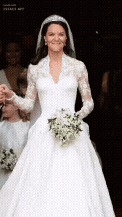 A Woman In A Wedding Dress Is Holding A Bouquet Of White Flowers GIF