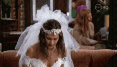 A Woman In A Wedding Dress Is Sitting On A Couch In A Living Room . GIF
