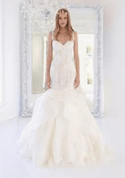 A Woman In A Wedding Dress Is Standing In Front Of A Window In A Room . GIF