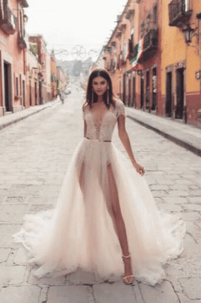 A Woman In A Wedding Dress Is Walking Down A Street . GIF