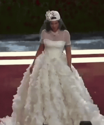 A Woman In A Wedding Dress Is Wearing A Baseball Cap And Veil . GIF
