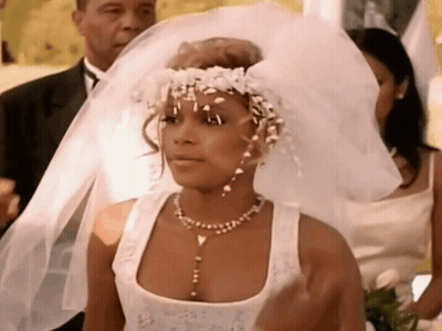 A Woman In A Wedding Dress Is Wearing A Veil And A Flower Crown . GIF