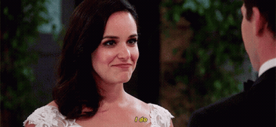A Woman In A Wedding Dress Says I Do While Looking At A Man In A Suit . GIF