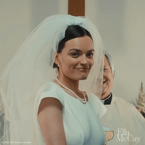 A Woman In A Wedding Dress With A Veil And A Pearl Necklace GIF