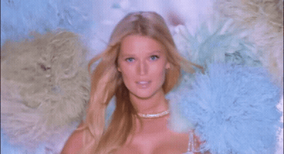 A Woman In A White Bra Is Surrounded By Feathers GIF