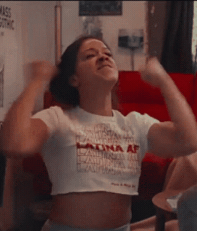 A Woman In A White Crop Top Is Flexing Her Muscles . GIF