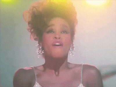 A Woman In A White Dress And Earrings Is Singing GIF