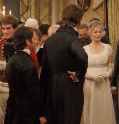A Woman In A White Dress And Gloves Stands In A Crowd Of People GIF