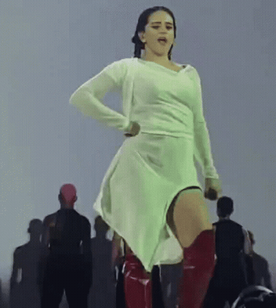 A Woman In A White Dress And Red Boots Is Dancing On Stage . GIF
