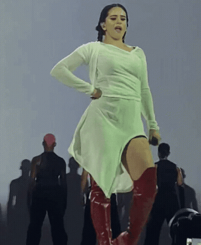 A Woman In A White Dress And Red Boots Stands On Stage GIF
