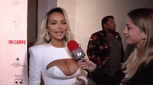 A Woman In A White Dress Is Being Interviewed With A Microphone . GIF