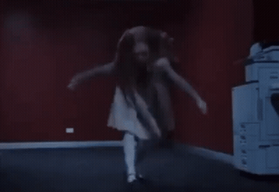 a woman in a white dress is dancing in a dark room in front of a printer .