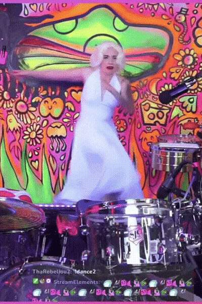 A Woman In A White Dress Is Dancing In Front Of A Drum Set That Says Sis On It GIF
