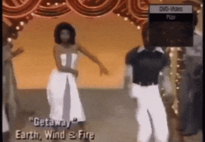 A Woman In A White Dress Is Dancing In Front Of A Dvd Player That Says Dvd Video Play GIF