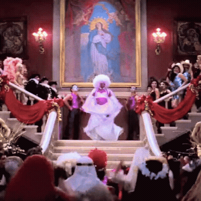 A Woman In A White Dress Is Dancing In Front Of A Large Painting GIF