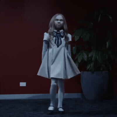 A Woman In A White Dress Is Dancing In Front Of A Potted Plant GIF