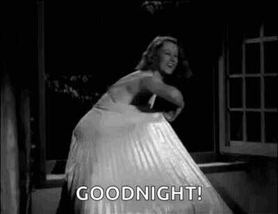 A Woman In A White Dress Is Dancing In Front Of A Window And Says `` Goodnight '' . GIF