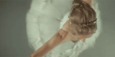 A Woman In A White Dress Is Dancing In The Water . GIF
