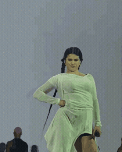 A Woman In A White Dress Is Dancing On Stage . GIF