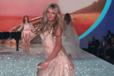 A Woman In A White Dress Is Dancing On The Runway GIF