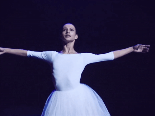 A Woman In A White Dress Is Dancing With Her Arms In The Air GIF