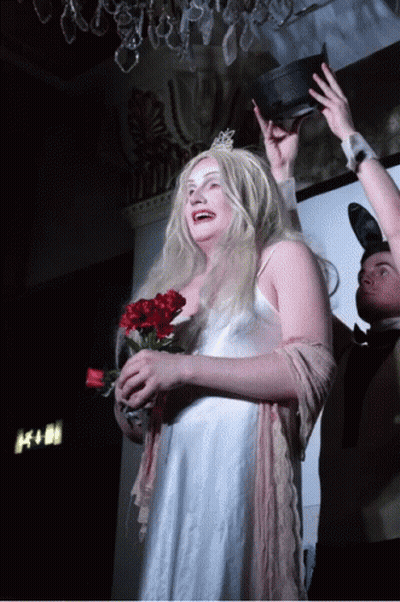 A Woman In A White Dress Is Holding A Bouquet Of Red Flowers GIF
