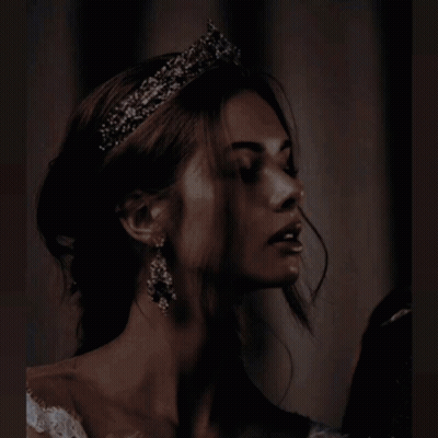 A Woman In A White Dress Is Holding A Candle In Her Hands GIF