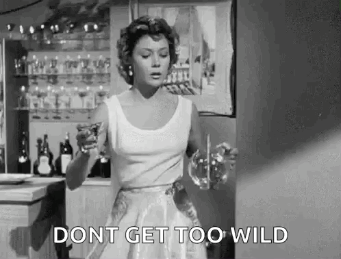 A Woman In A White Dress Is Holding A Glass Of Wine And A Glass Of Water . GIF