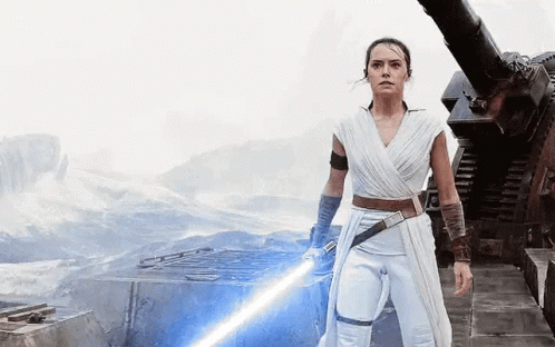 A Woman In A White Dress Is Holding A Light Saber . GIF