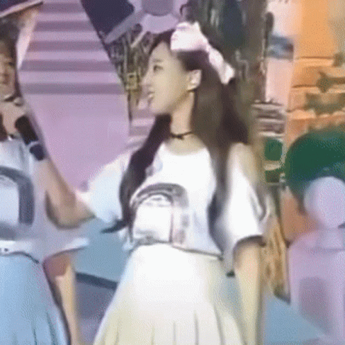 A Woman In A White Dress Is Holding A Microphone In Her Hand GIF