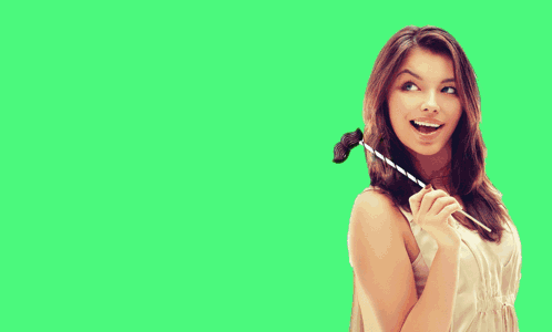 A Woman In A White Dress Is Holding A Straw In Front Of A Green Field GIF