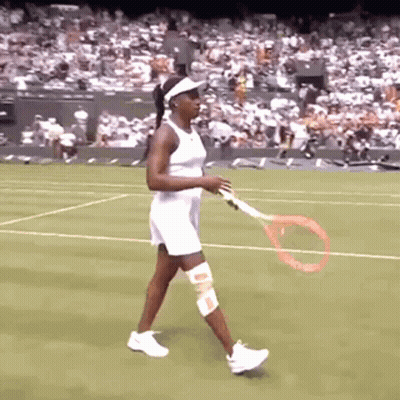 A Woman In A White Dress Is Holding A Tennis Racquet On A Tennis Court GIF