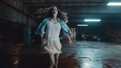 A Woman In A White Dress Is In A Parking Garage GIF
