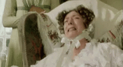 A Woman In A White Dress Is Laying In A Hospital Bed And Crying . GIF