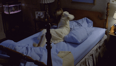 A Woman In A White Dress Is Laying On A Bed GIF