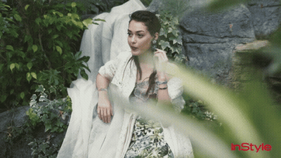 A Woman In A White Dress Is Laying On A Rock With Instyle Written On The Bottom Left GIF