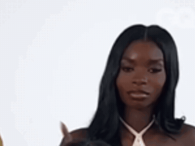 A Woman In A White Dress Is Pointing At Something . GIF