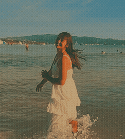 A Woman In A White Dress Is Running Into The Water GIF