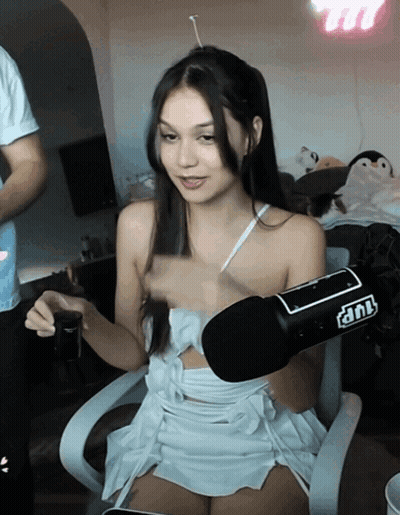 A Woman In A White Dress Is Sitting In Front Of A Microphone That Says Tnt On It GIF