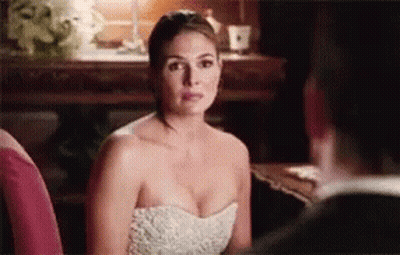 A Woman In A White Dress Is Sitting Next To A Man In A Suit And Looking At Him . GIF