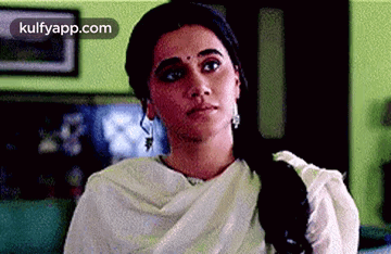 A Woman In A White Dress Is Sitting On A Couch In A Living Room . GIF