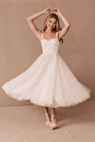 A Woman In A White Dress Is Smiling And Dancing GIF