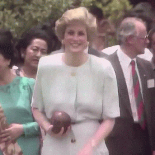 A Woman In A White Dress Is Smiling While Holding An Apple GIF