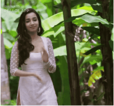 A Woman In A White Dress Is Standing In A Jungle . GIF
